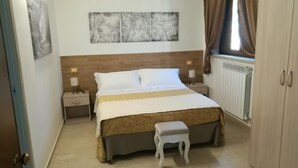 Un dormitorio con cama, mesitas de noche, un banco y una obra de arte en la pared.