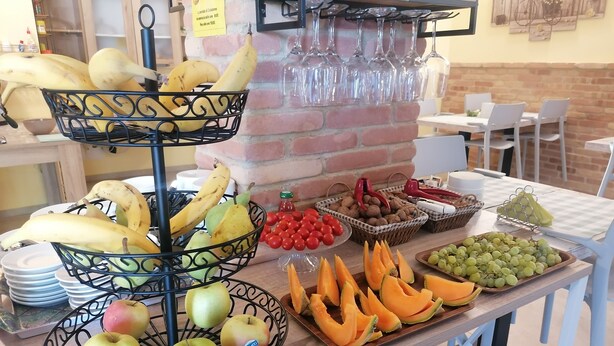 Un bufé de desayuno con diversas frutas, nueces y una estructura para copas de vino.