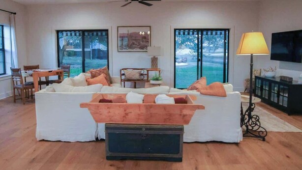 A spacious living room with a white sofa set, a wooden coffee table, and a television on a stand. - Rest & Relax | Pool | Countryside View | Sleeps 6 (Fayetteville)