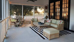 Une véranda abritée avec une table à manger et des chaises, un canapé et un ventilateur de plafond.