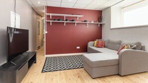 Una sala de estar moderna con un sofá gris, un televisor de pantalla plana y una alfombra estampada.
