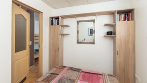 Un dormitorio con cama, armario, espejo y puerta que da al baño.