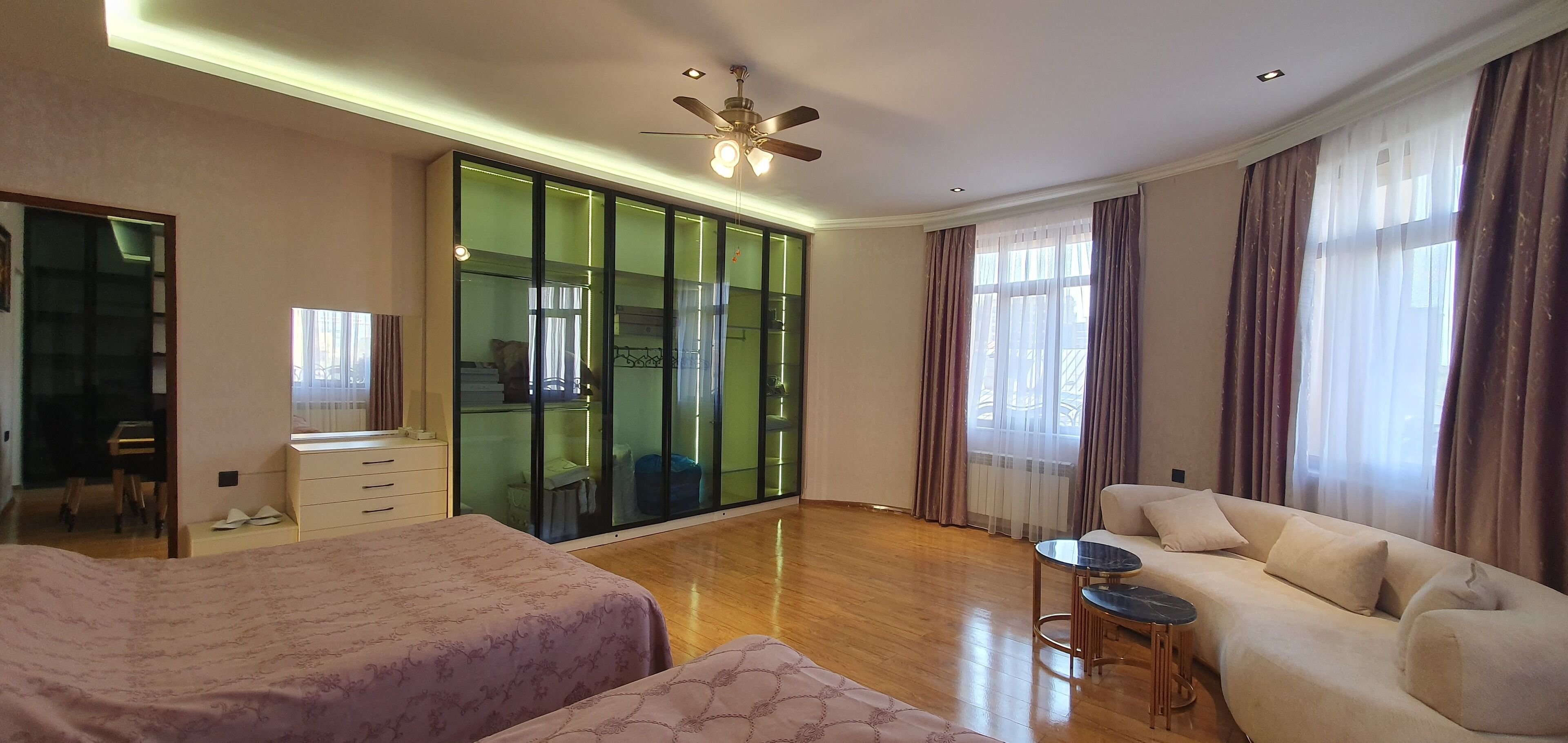 Een moderne hotelkamer met een groot bed, een slaapbank, een klein tafeltje en een glazen schuifdeur naar een balkon.