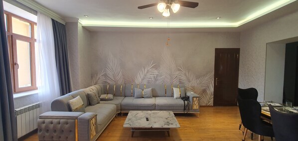 A living room with a sectional sofa, a coffee table, and a dining area with chairs.