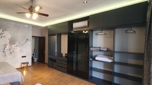 A bedroom with a bed, a ceiling fan, a wardrobe with hanging space, and a wall with floral artwork. - The Pearl of Nizami Street (Baku)
