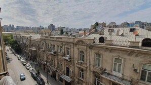 A row of historic buildings with balconies, a street with parked cars, and a cityscape in the background. - The Pearl of Nizami Street (Baku)