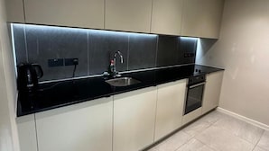 A modern kitchen with a black countertop, stainless steel backsplash, and a built-in oven. - Apartment - Sleeps 4, Pets Allowed & Free Parking (Manchester)
