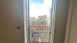 A window with a view of a cityscape, including buildings and a construction site. - Apartment - Sleeps 4, Pets Allowed & Free Parking (Manchester)