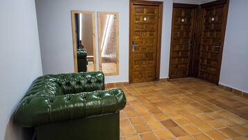 Una habitación con un sofá de cuero verde, dos puertas de madera y suelo de baldosas.