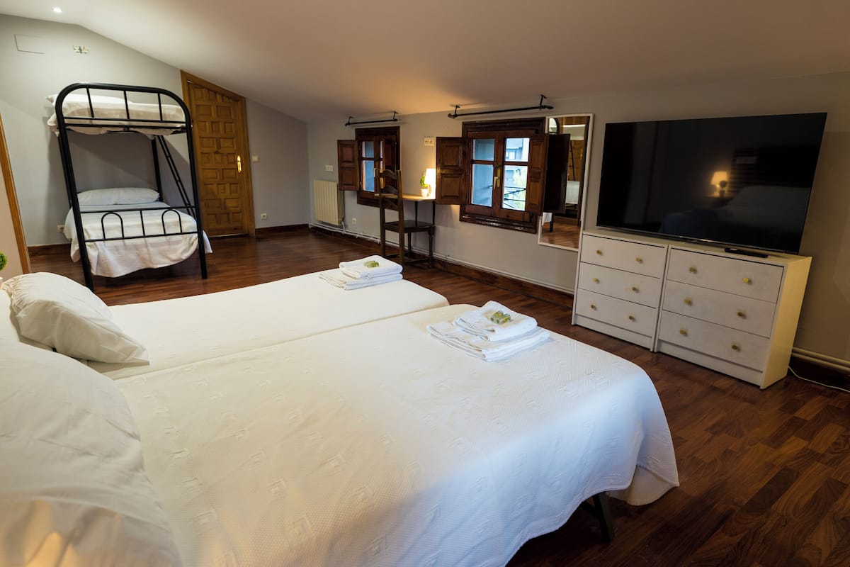 Quarto de hotel com duas camas, uma televisão, uma escrivaninha e uma cadeira.