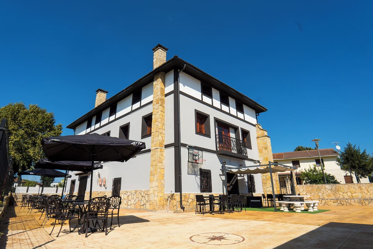 Um edifício de dois andares com área de estar ao ar livre e chaminé de pedra.