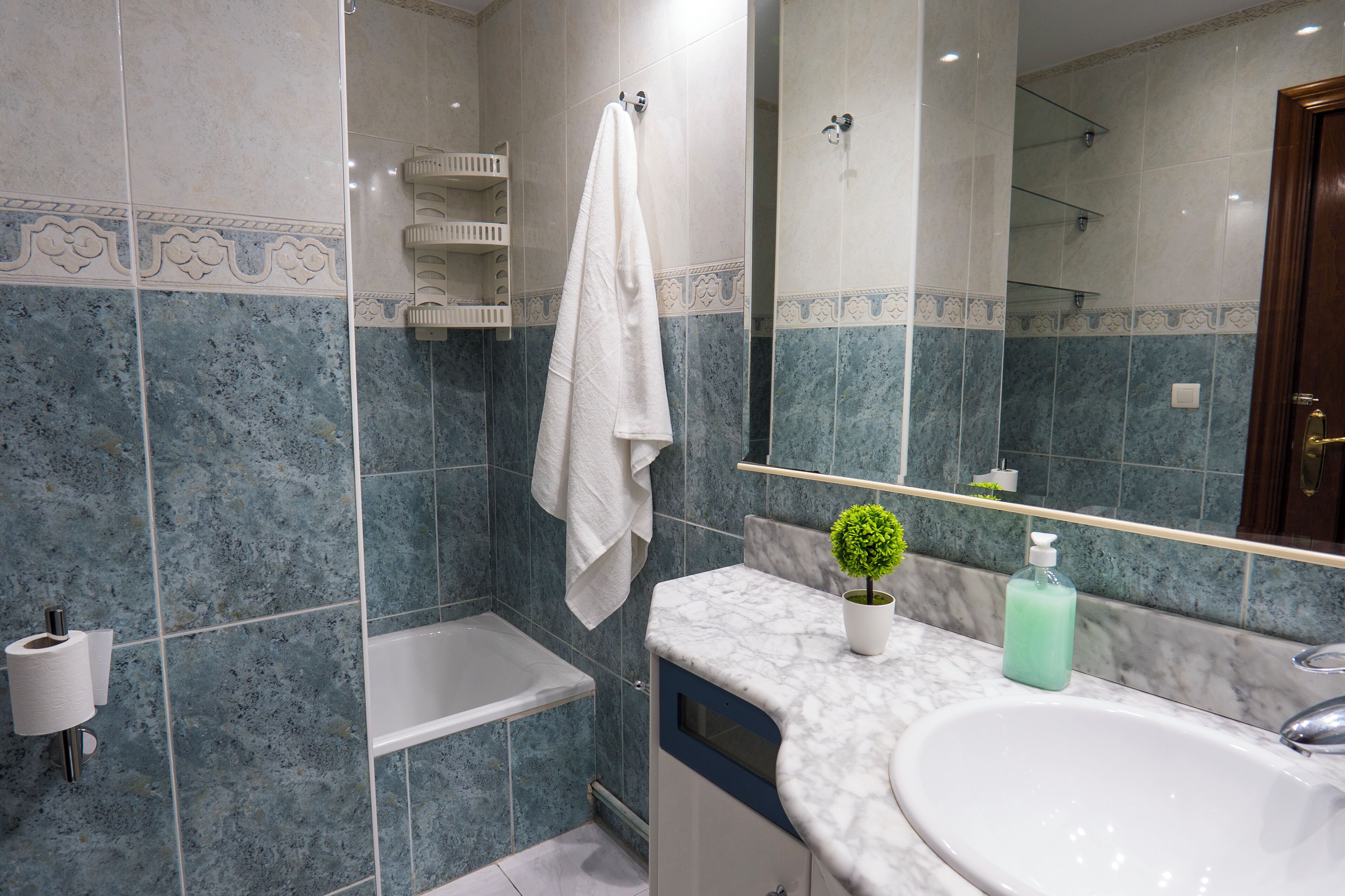 Un baño con una bañera, un lavabo, un espejo y una toalla colgada en la pared.