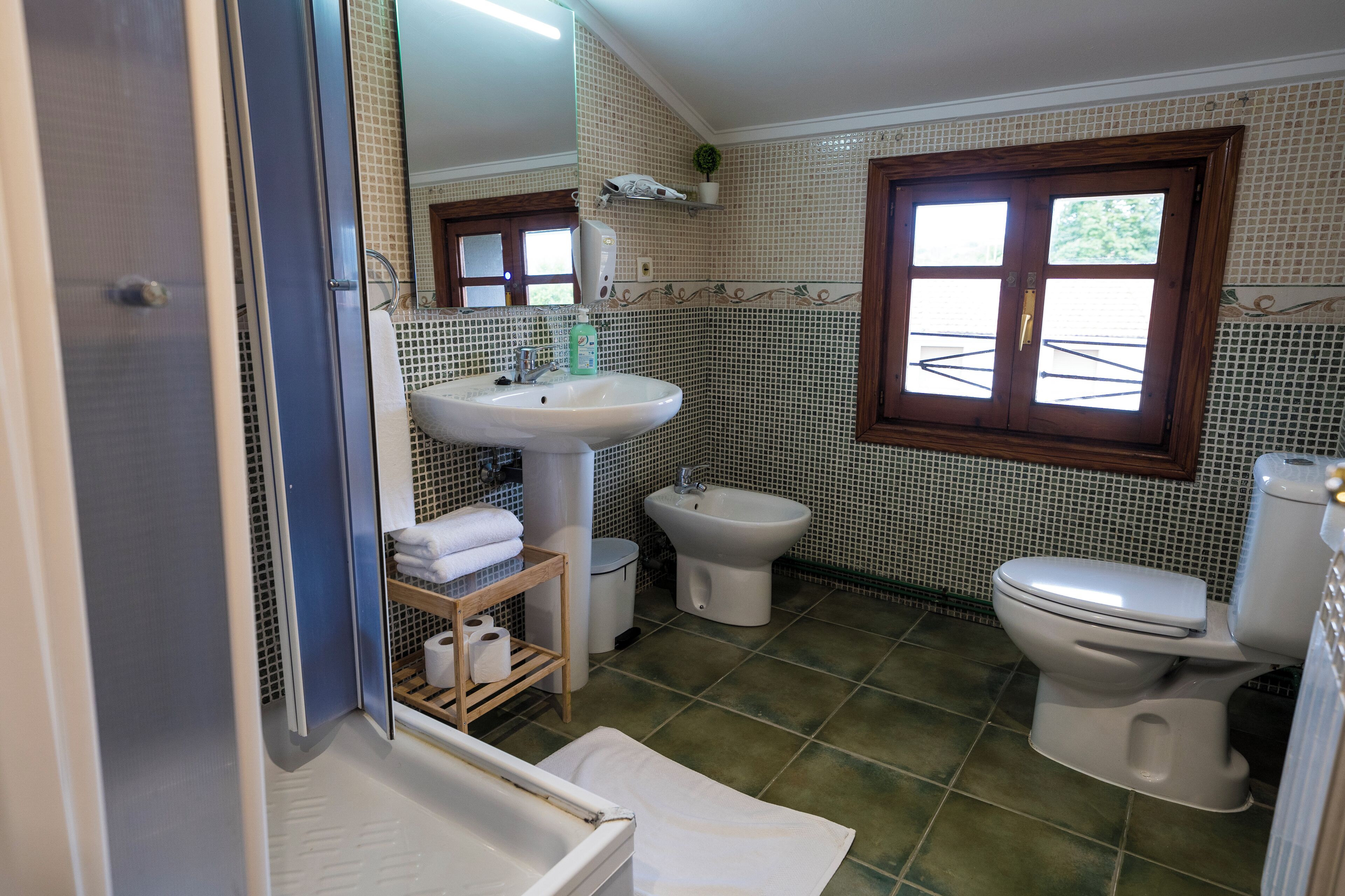 A bathroom with a sink, bidet, toilet, and a shower area.