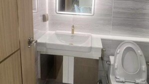 Un baño con lavamanos blanco, espejo y retrete.