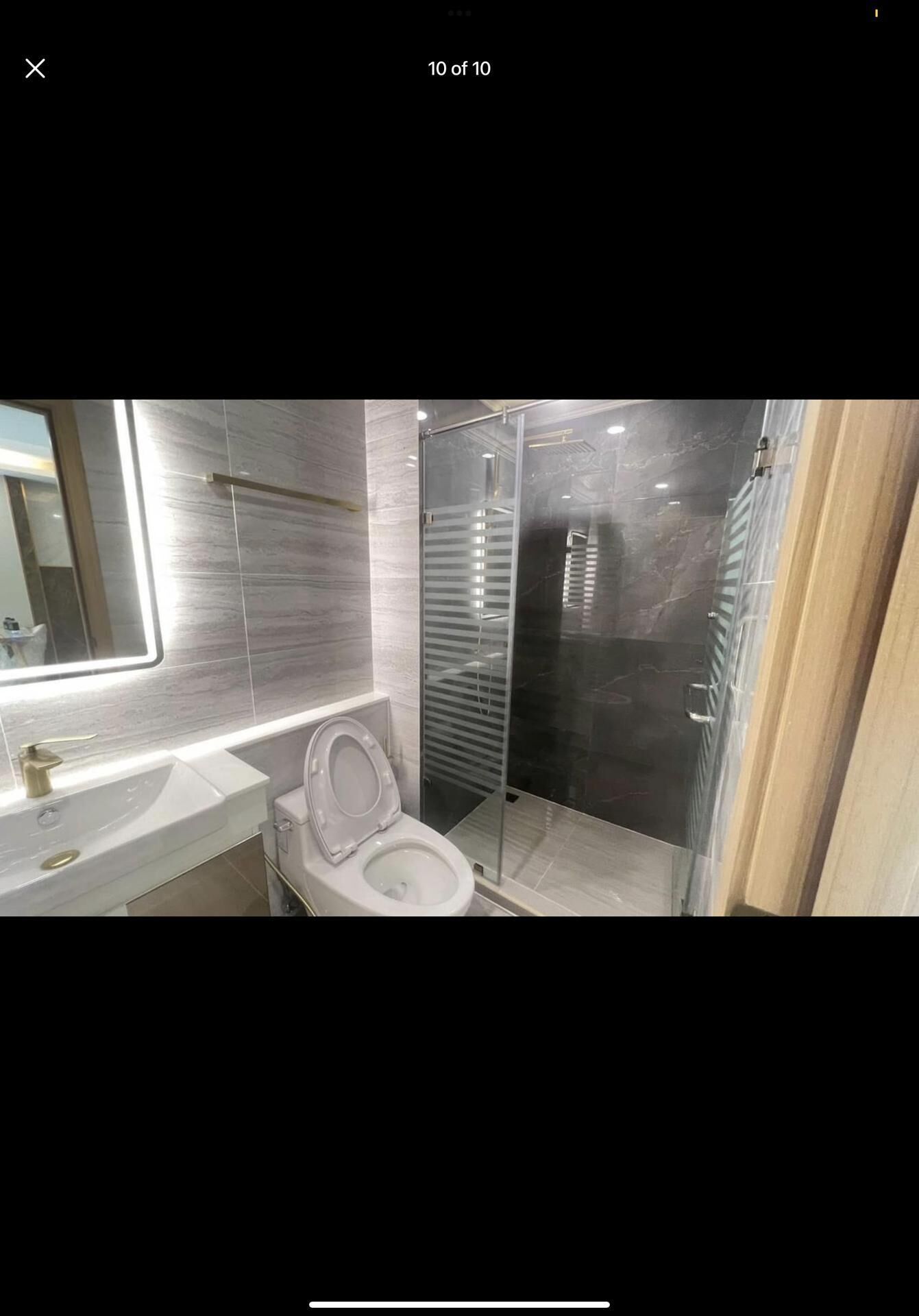 A modern bathroom with a glass-enclosed shower, a white sink, and a toilet.