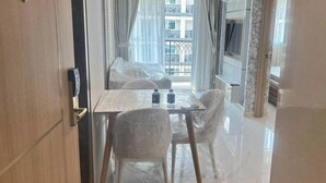 Habitación de hotel con una mesa de vidrio, dos sillas, una cama y un balcón con vistas al edificio.