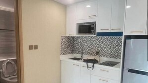 Una cocina moderna con armarios blancos, un salpicadero de azulejos blancos y negros, un microondas, una estufa y un refrigerador.
