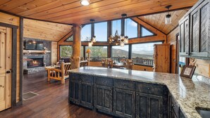 Eine geräumige Küche mit einer großen Kochinsel, Holzschränken und einem Kamin aus Stein.