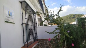 A white building with a stone wall and a metal gate.