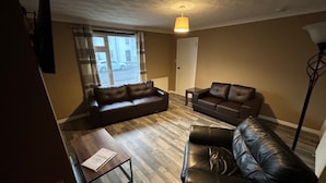 A living room with two leather sofas, a coffee table, and a floor lamp. - 2bedroom-1bathroom-patio-wifi (Auchterarder)