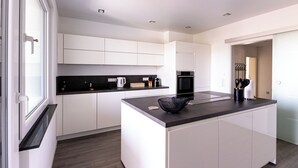 Een moderne keuken met witte kasten, een zwart aanrecht en een ingebouwde oven.