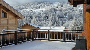 A wooden cabin with a balcony overlooking a snow-covered forest and mountains. - La Tanière : Exceptional Alpine chalet with heated pool & sauna - 14 pers (Vars)