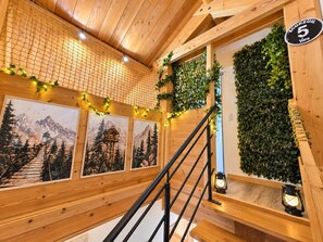 Een houten trap met een zwarte leuning, omgeven door houten wanden en een houten plafond.