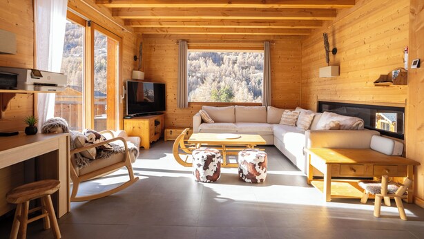 A cozy cabin interior with a wooden interior, a sofa, a TV, and a dining area. - La Tanière : Exceptional Alpine chalet with heated pool & sauna - 14 pers (Vars)