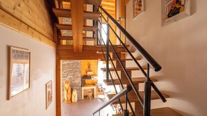 A wooden staircase with a metal handrail leading to a living area with a stone wall and wooden furniture. - La Tanière : Exceptional Alpine chalet with heated pool & sauna - 14 pers (Vars)