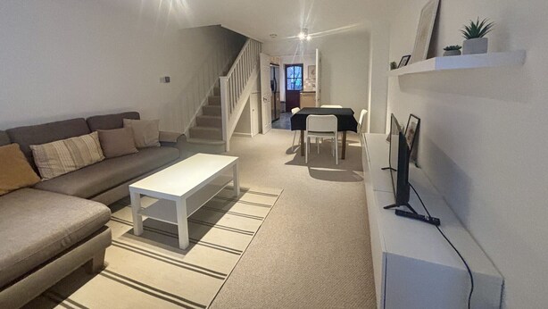 Een moderne woonkamer met een bank, salontafel en een eetgedeelte met tafel en stoelen.