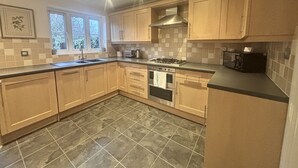 Een moderne keuken met houten kastjes, een gasfornuis, een magnetron en een vaatwasser.