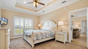 A bedroom with a bed, bedside tables, a ceiling fan, and a window with blinds.