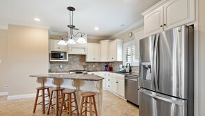 A modern kitchen with a central island, stainless steel appliances, and white cabinetry.