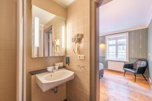 Une salle de bain équipée d’un lavabo, d’un miroir et d’un sèche-cheveux.