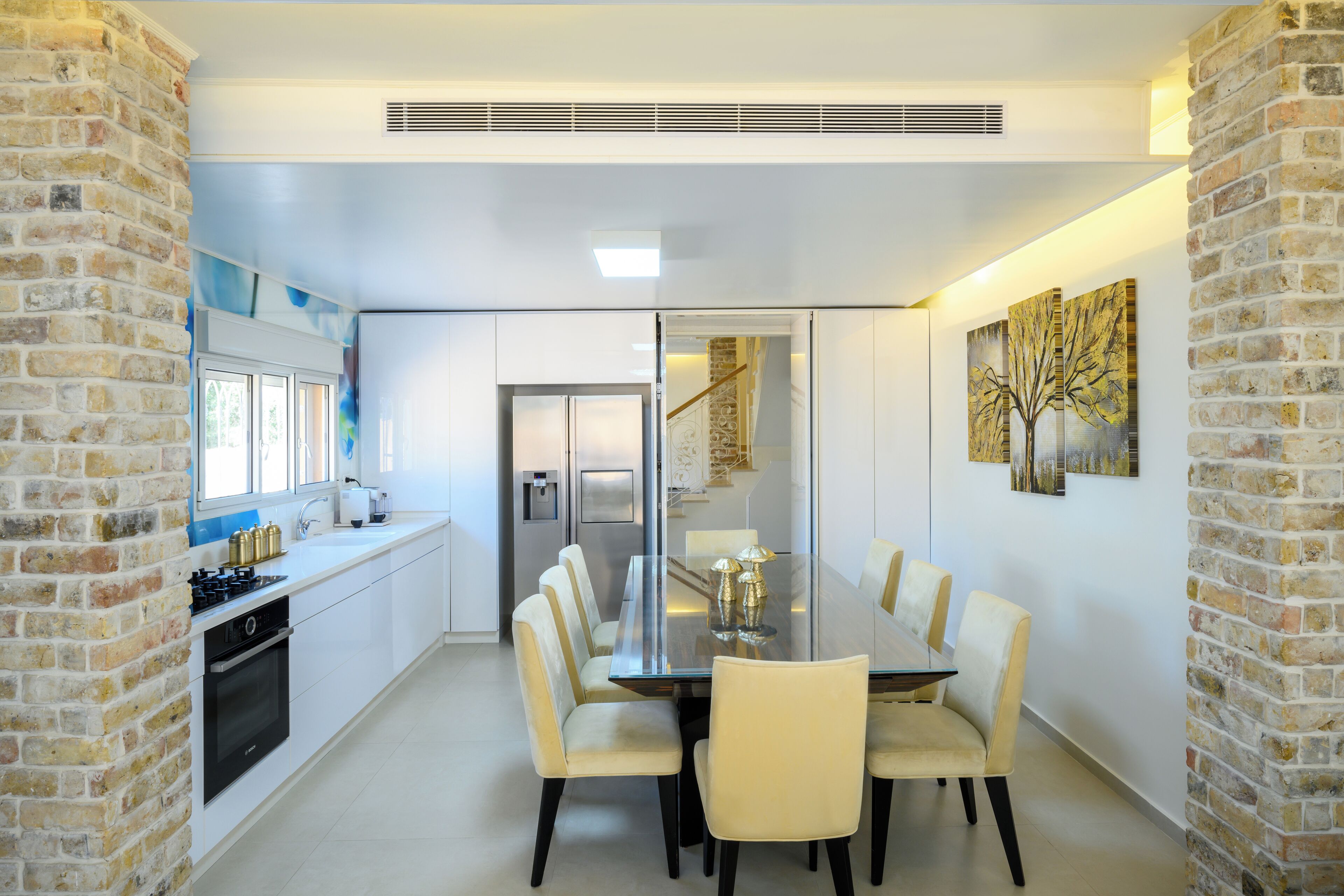 A modern kitchen with white cabinets, a built-in oven, and a stainless steel refrigerator.