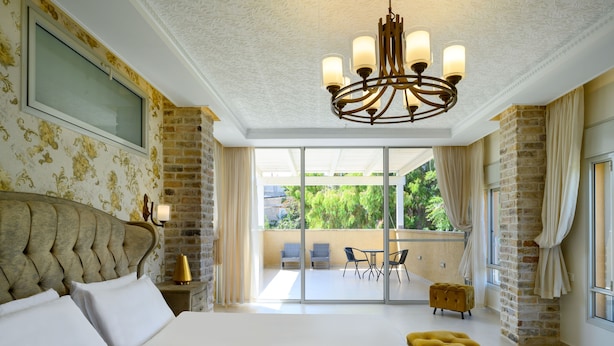Un'ampia camera da letto con un grande letto, un lampadario e un balcone con sedie.