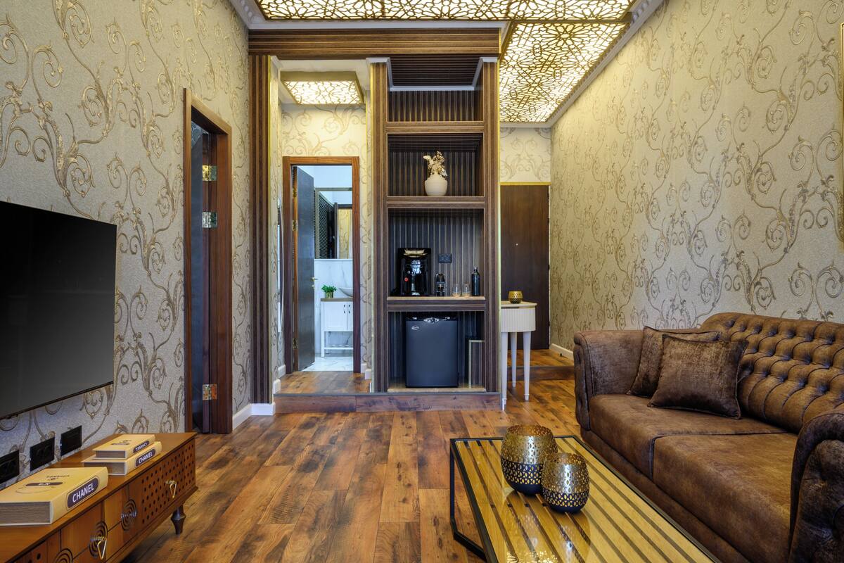 Un salon doté d’un grand téléviseur à écran plat, d’un canapé en cuir marron, d’une table basse en bois et d’un mur décoratif orné d’un motif.