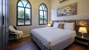 Una camera da letto con un grande letto, due finestre ad arco, un lampadario, un condizionatore d'aria e un elemento decorativo a parete.