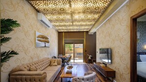 Un soggiorno moderno con un divano, un tavolino in legno e una televisione. Una parete decorata con un motivo e un soffitto con design geometrico.