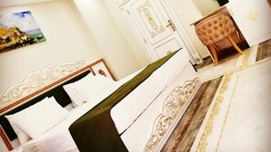 A hotel room with a bed, a chair, a desk, and a door. - biçen hotel (Midyat)