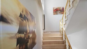 A staircase with beige steps and gold handrails, leading to a landing with a framed painting. - biçen hotel (Midyat)
