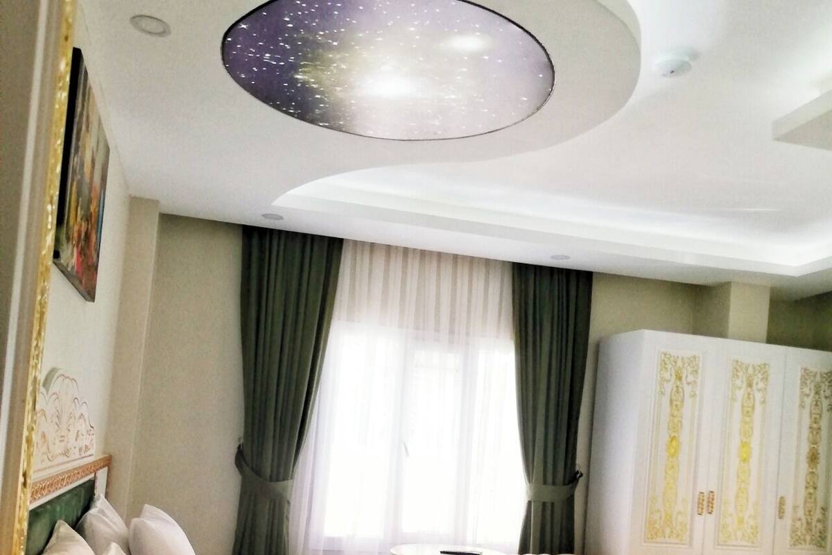 A hotel room with a bed, a chair, a small table, and a wardrobe.