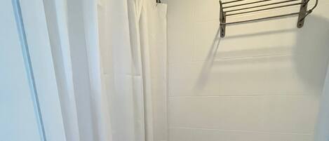 Un baño pequeño y estrecho con inodoro, bidé, azulejos blancos y cortina de ducha.