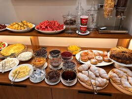 Un bufé con una variedad de alimentos, entre ellos frutas, pasteles y salsas.