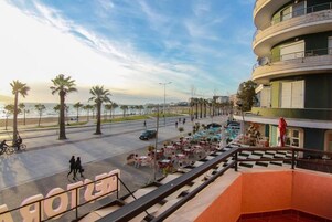 Un hotel con terraza exterior, vistas a la playa y una fachada de edificio curva.