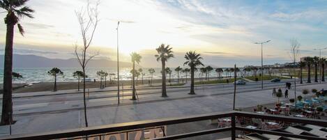 Vista costera con palmeras, una carretera y un área con café.