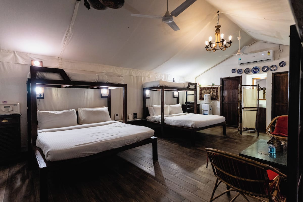 A room with two bunk beds, a table with a chair, a ceiling fan, and a chandelier.