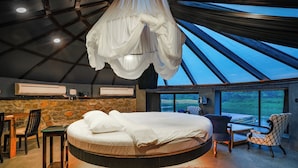 A bedroom with a hanging canopy bed, stone wall, and a view of the outdoors. - Anchaviyo By Zuper (Vada)