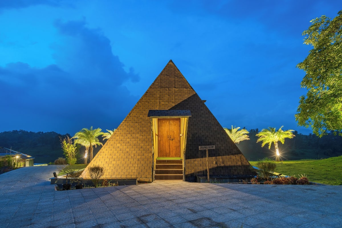 A pyramid-shaped building with a wooden door and steps leading up to it.