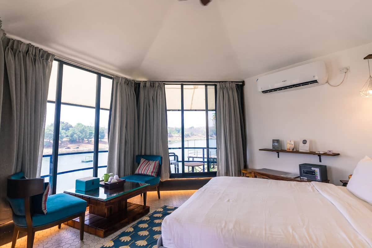 A hotel room with a bed, a desk, a chair, a table, and a view of the outdoors.